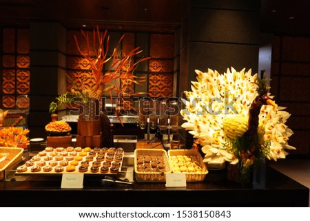  Breakfast or ood counter in a hotel. Doughnuts and cookies along with a peacock made of fruits and vegetables.                             