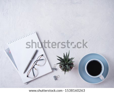Business flat lay with cup of coffee, cicculent, notebook, pen and eye glasses on white beton background.Image top view and copy space