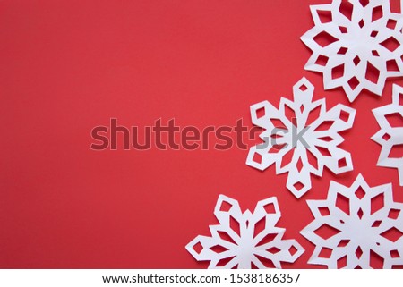 Many white paper snowflakes arranged on the right side of an image on red background. Photot with copy blank space.