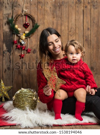 Beautiful mom and daughter dressed alike with red pullovers on Christmas wooden background. Xmas holidays concept. Family lover portrait. Merry Christmas and happy holidays.