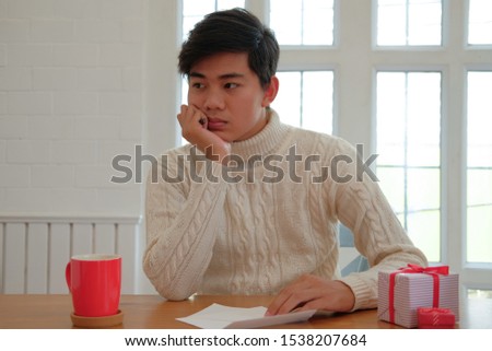 man wearing cream sweater thinking what to write on christmas letter greeting card holiday wishes. xmas celebration