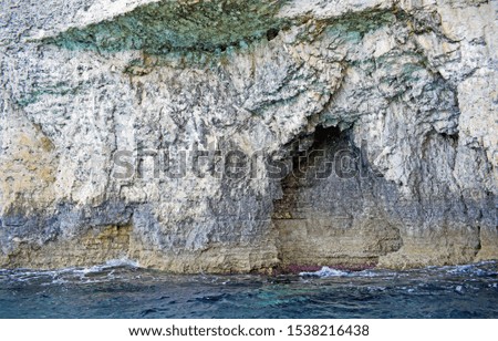 Inside a sea cave with the blue Mediterranean sea water and the coral at sea level.