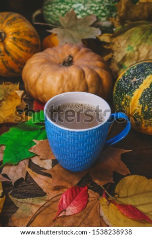cup of coffee with milk on a background of autumn leaves and pumpkins.