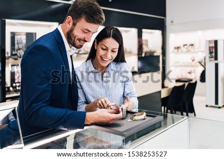 Beautiful couple enjoying in shopping at modern jewelry store. Close up shot of human hand holding expensive watch. Royalty-Free Stock Photo #1538253527