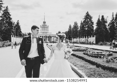 Happy newlyweds walking on city street after wedding ceremony. Black and white photo