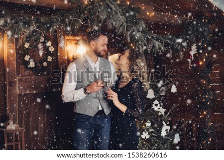 Beautiful couple with champagne under Christmas wreath.