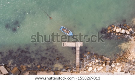 Lonely fishing boat and wooden pier in turquoise ocean, sea. Aerial photo, top view