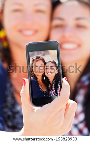 Beautiful girlfriends taking a self shot with phone.