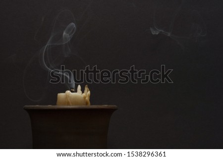 Smoke from a wax candle on a dark background. Concept of divination, magic, ritual. Copy space. Royalty-Free Stock Photo #1538296361