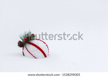 Red and white ball on a snowy Christmas tree