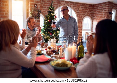 Family and friends dining at home celebrating christmas eve with traditional food and decoration, making a toast for new year best wishes