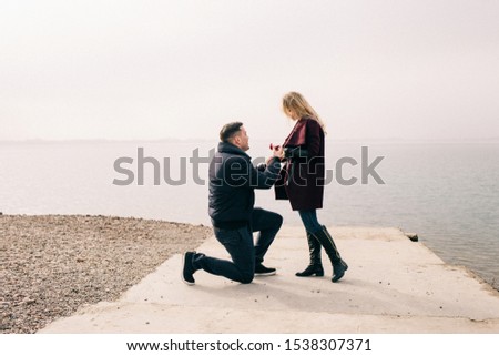 the guy makes an offer to the girl on the pier Royalty-Free Stock Photo #1538307371
