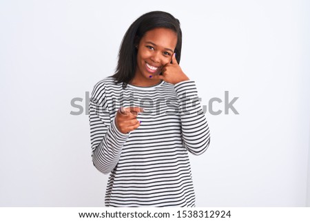 Beautiful young african american woman wearing winter sweater over isolated background smiling doing talking on the telephone gesture and pointing to you. Call me.