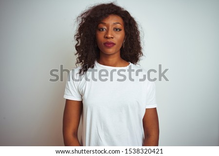 Young african american woman wearing t-shirt standing over isolated white background Relaxed with serious expression on face. Simple and natural looking at the camera. Royalty-Free Stock Photo #1538320421