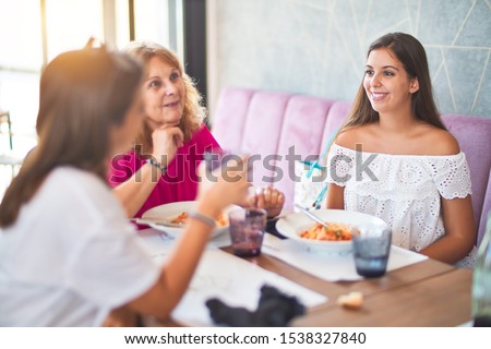 Beautiful group of women sitting at restaurant eating food speaking and smiling