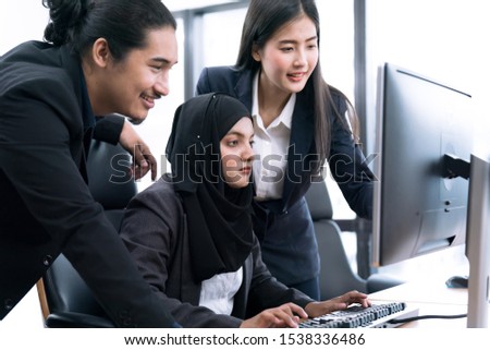 A team of three confident modern businessmen working together on a computer.
