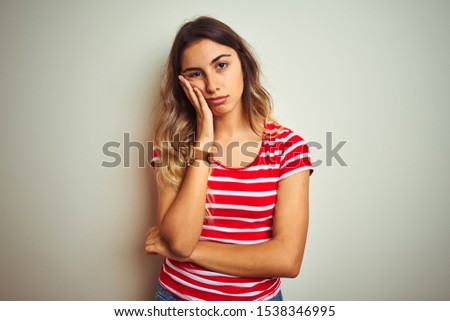 Young beautiful woman wearing red stripes t-shirt over white isolated background thinking looking tired and bored with depression problems with crossed arms.