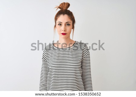Redhead woman wearing navy striped t-shirt standing over isolated white background Relaxed with serious expression on face. Simple and natural looking at the camera.