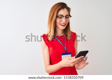 Redhead businesswoman wearing id card using smartphone over isolated white background with a happy face standing and smiling with a confident smile showing teeth