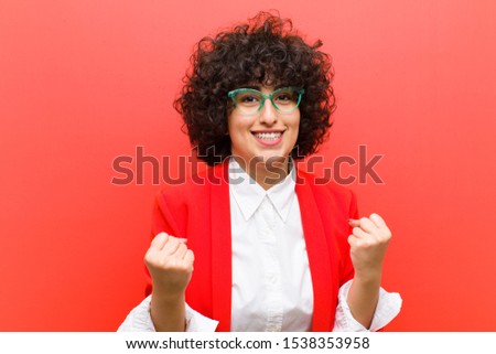 young pretty afro woman shouting triumphantly, laughing and feeling happy and excited while celebrating success