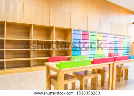 Interior of kindergarten classroom consist desks, chairs and lockers.