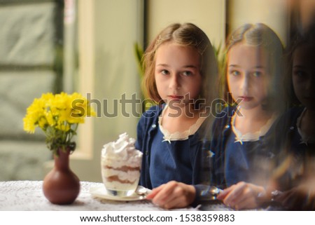 Little girl drinking hot chocolate in a cafe. schoolgirl drinks cocoa in a cafe. girl after classes in a coffee house drinks cocoa and eats a dessert. Photos with warm tinting. Back to school