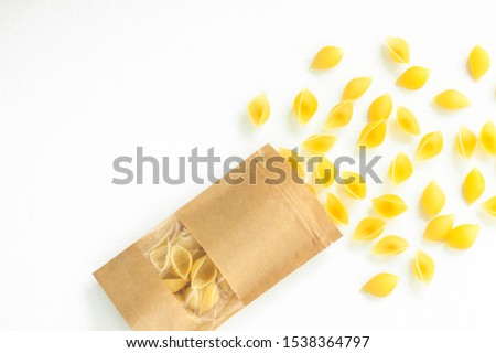 Pouch bag with pasta flatlay, top view. Packaging with transparent window isolated on white background. Package mockup for brand. Italian conchiglie or durum wheat shells. Copy space food photography.