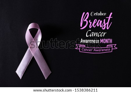 Pink ribbon on black paper background for supporting breast cancer awareness month campaign.