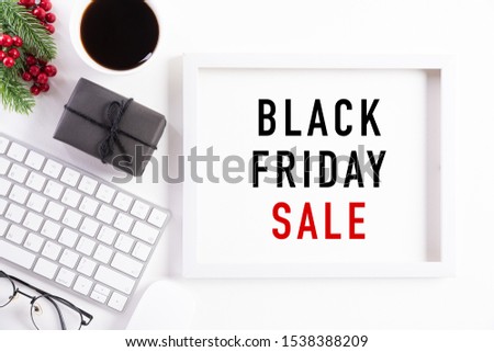 Black Friday Sale text on white picture frame with keyboard mouse coffee cup, gift box and Christmas tree decoration, red berries on white background. Shopping concept and black Friday composition.