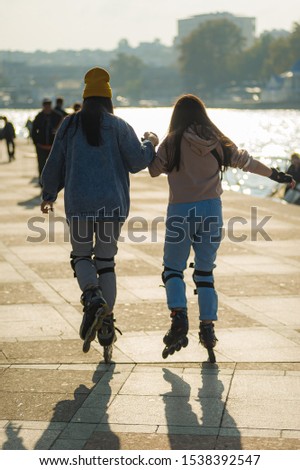 two girlfriends rollerblading in the city center