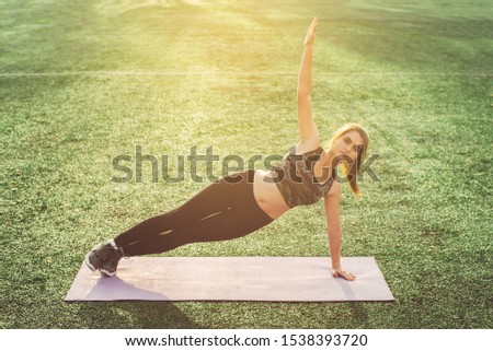 Healthy sports lifestyle. Young woman doing yoga in stadium. Side plank pose.