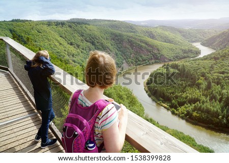 Tourists looking at Saarschleife in the Saarland, Germany seen from the lookout tower of the treetop path, called Baumwipfelpfad                           Royalty-Free Stock Photo #1538399828