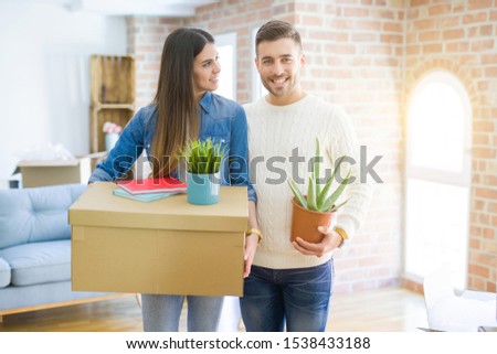 Beautiful young couple moving to a new house, smiling happy holding cardboard boxes at new apartment