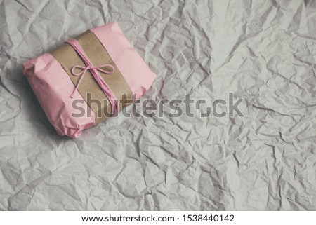 Soft pouch wrapped in craft paper and tie cord. Crumpled paper background texture. Delivery service. Online shopping. 