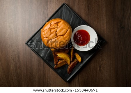 Big fresh burger with sauce and fries on black plate. American classic burger menu.