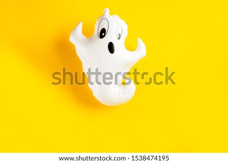 Inflatable white ghost as Halloween party decoration symbol on bright yellow background, top view, copy space
