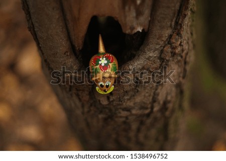 toy mouse looks down from a hole in a tree