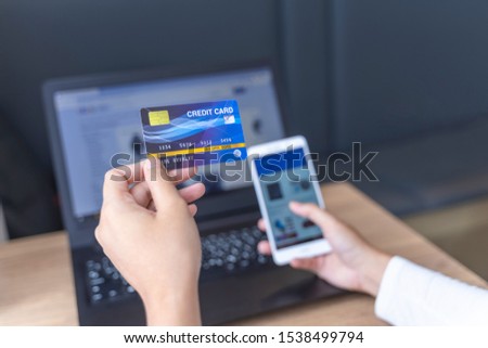 The concept is A woman using a laptop to find products On the online website And pay through the application on a mobile phone By credit card