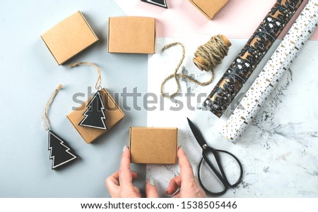 Female hand's wrapping christmas gifts, present boxes and decorating on tricolor background. Top view, flat lay concept. Happy New Year 2020