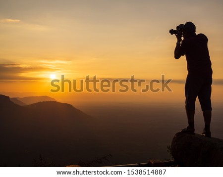 A photographer standing on the top of the hill At sunrise, there are clouds, fog at Pha Mor Daeng, Sisaket Province, Thailand, ASIA.