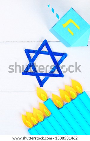 Menorah, dreidel, sevivon, the star of David with their own hands on a white wooden table. DIY for a child. Celebration of Chanukah