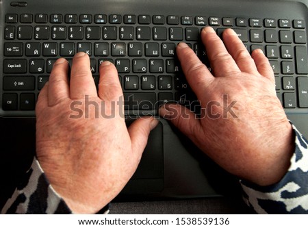 Old woman's hands and laptop. Pc keyboard of black color. Know more about modern technologies.