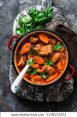 Cozy comfort winter autumn food - spicy braised crock pot beef in a pot on a rustic wooden board on a dark background, top view                      Royalty-Free Stock Photo #1538553242