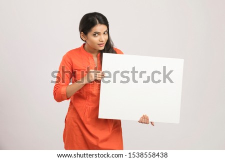 Attractive Indian woman holding white board.