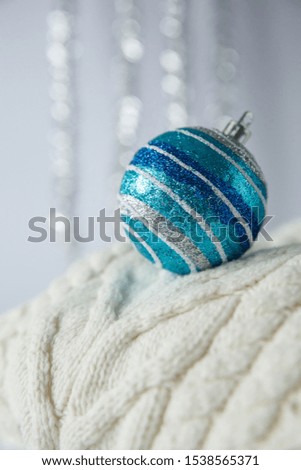 Christmas. Christmas toy silver, blue striped ball with sparkles on a white knitted woolen sweater.