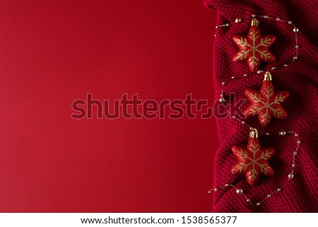 Red Christmas background with red Christmas toys and beads on a red knitted fabric.