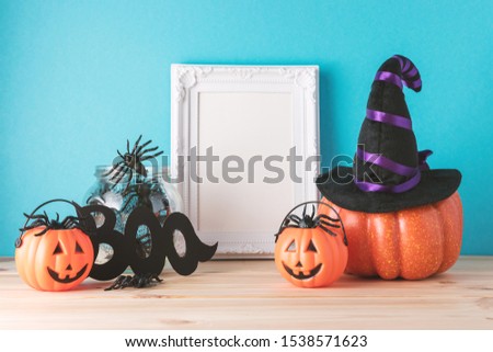 Holiday concept with Halloween pumpkin decor and photo frame on wooden table. Creative Halloween minimal concept.