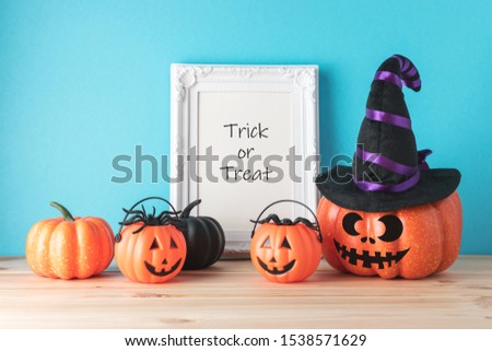Holiday concept with funny Halloween pumpkin decor and photo frame on wooden table. Creative Halloween minimal concept.