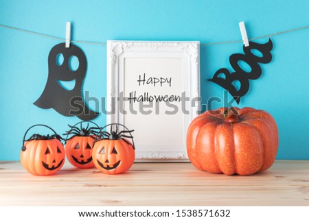 Holiday concept with Halloween pumpkin decor and photo frame on wooden table. Creative Halloween minimal concept.