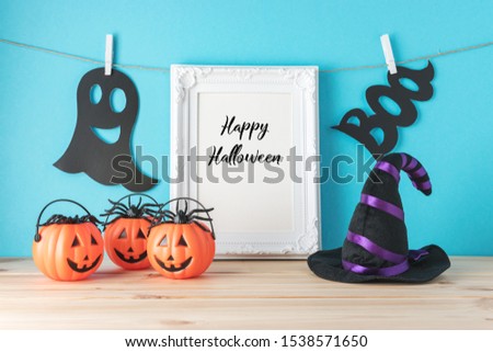 Holiday concept with Halloween pumpkin decor, witch hat and photo frame on wooden table. Creative Halloween minimal concept.